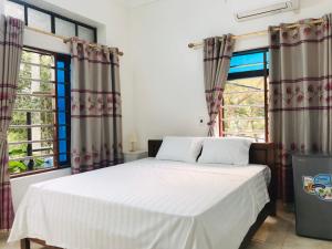 宁平Tam Coc Sunset Homestay的一间卧室设有一张床和两个窗户。
