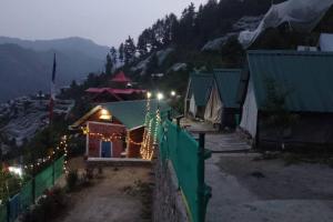 纳尔卡恩达Wild Himalaya Glamping Camp的山间装饰着圣诞灯的房子