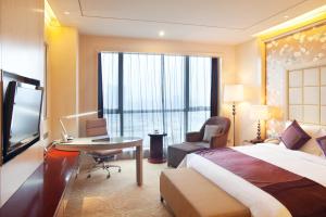 襄阳襄阳富力皇冠假日酒店 的酒店客房配有一张床、一张书桌和一台电视。