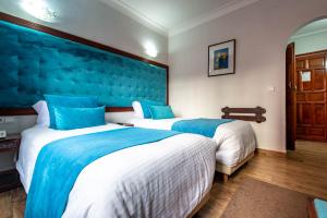 马拉喀什Hotel Oudaya & Spa的两张位于酒店客房的床,拥有蓝色的墙壁