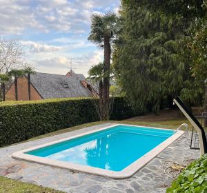 莱萨VSC Apartment - Appartamento in villa storica vista lago e piscina的一座绿树成荫的庭院中的蓝色游泳池