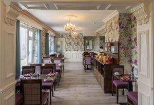 基拉尼城堡旅舍的用餐室配有桌椅和花卉壁纸