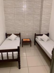 安格拉杜斯雷斯Hotel Pousada AngraAntiga的一间设有两张床和一张桌子的房间