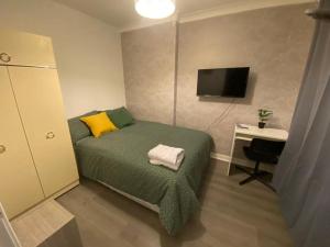 格拉斯哥Culbin Drive, Glasgow的一间卧室配有一张床、一张书桌和一台电视