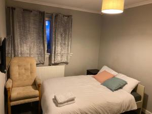 格拉斯哥Culbin Drive, Glasgow的卧室配有床、椅子和窗户。