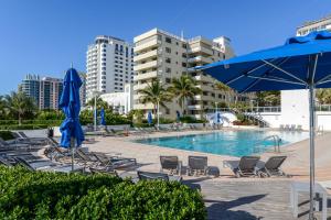 迈阿密海滩Decoplage Paradise - Unit A的一个带椅子和蓝伞的游泳池