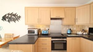 BishopstonRedcliffe Apartments K的厨房配有木制橱柜和黑色台面