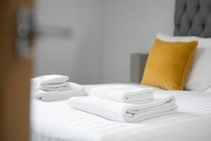 布伦特伍德S/KING BED ONE BEDROOM FLAT的床上的毛巾堆,有黄色枕头