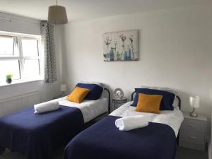 LighthorneAccomodation for contractors & professionals 3 bed house with parking的一间卧室配有两张带蓝色和黄色枕头的床