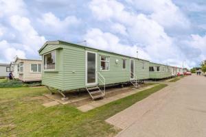 大雅茅斯8 Berth Caravan At California Cliffs Holiday Park In Norfolk Ref 50007d的停在草地上的一排移动房屋