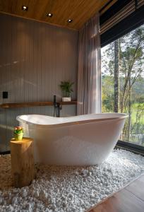 乌鲁比西Green Barn Hotel & Bistro的带窗户的浴室内的白色浴缸