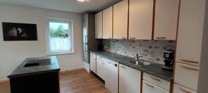 滨湖席弗灵Ferienhaus Familienzeit的厨房配有白色橱柜、水槽和窗户。