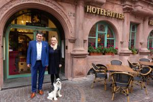 海德堡Hotel zum Ritter St. Georg的男人和女人,狗在旅馆前