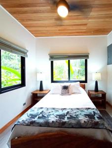 蓬塔乌巴Dragonfly Beach Retreat Beachfront Casitas-Adult Only的一间卧室设有一张大床和两个窗户。