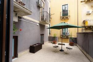 卡塔尼亚Casta Diva Holiday Rooms的一个带绿色遮阳伞和椅子及桌子的庭院