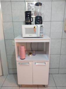 伊瓜苏Apartamento temporário Vila Yolanda的配备了微波炉和咖啡机的白色橱柜