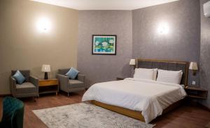 伊斯兰堡Hillside Residence E-7 by Paramount Hospitality的一间卧室配有一张大床和两把椅子