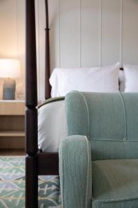 汉普顿贝斯Canoe Place Inn & Cottages的一间卧室配有一张床和一把绿色椅子