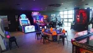 SinanC-One Resort Jaeundo的一间设有许多街机游戏、桌子和凳子的房间