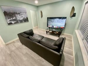 盖恩斯维尔Serene renovated oasis near downtown area的客厅配有黑色真皮沙发和平面电视。
