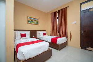 MeulabohRedDoorz Syariah @ Jalan Gajah Mada Meulaboh的一间卧室配有两张带红色枕头的床