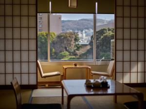 伊东伊东遊季亭日式旅馆的客房设有桌子和大窗户。
