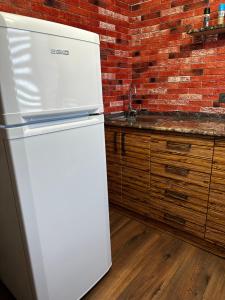 巴尔喀什Комфортабельная однокомнатная квартира的厨房里设有白色冰箱,有砖墙