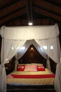 清迈Capital O 75421 Baan Singkham Boutique Resort的一间卧室配有一张带红色枕头的天蓬床