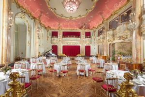 布拉格波西米亚大酒店的宴会厅配有白色桌子和红色椅子