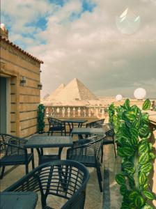 开罗Crowne Pyramids view inn的一组桌子和椅子,后面有金字塔