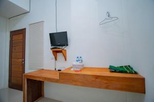 TingkeumRedDoorz Syariah near Rembele Airport Bener Meriah的一张木桌,墙上有电视