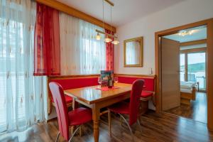 圣卡尼兹enJoy Appartements的一间带木桌和红色椅子的用餐室