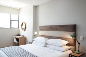 比勒陀利亚莱克斯精品酒店的卧室配有白色的床铺和白色的枕头