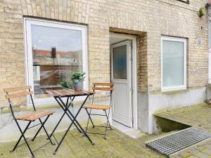 奥尔堡aday - Charming Studio close to the Football Stadium的庭院设有两把椅子、一张桌子和一扇窗户。