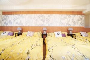 大阪MATATABI STAY Daikokucho的一间卧室配有两张带黄床单和两盏灯的床。