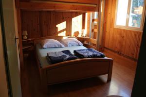 Foncine-le-BasLes Morillons的木制客房内的一张床位,上面有两个枕头