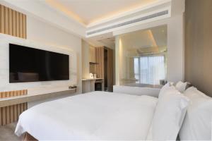 礁溪Gamalan Star Hotel的卧室配有白色的床和平面电视。