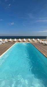 敖德萨Apart-Hotel Poseidon的一个带椅子的游泳池,背景是大海