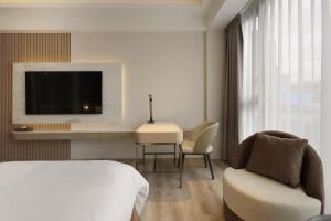 礁溪Gamalan Star Hotel的一间卧室配有一张床、一张书桌和一台电视。