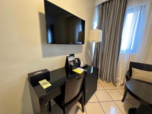 阿克拉机场东橡树广场酒店的酒店客房设有一张桌子,墙上配有电视