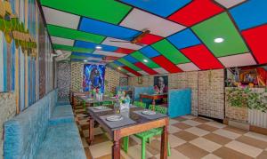 麦罗肯机Treebo Trend Roshan House的餐厅拥有色彩缤纷的天花板,配有桌椅