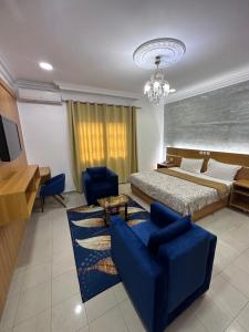 布拉柴维尔Hotel de l'Aeroport的一间卧室配有一张床、一张蓝色的沙发和椅子