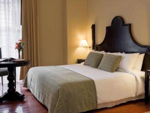 库斯科诺富特库斯科酒店的一间卧室配有一张白色大床和黑色床头板