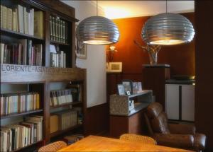里米尼卡萨曼奇尼住宿加早餐旅馆的图书馆,配有两盏灯,一把椅子和书籍
