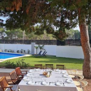 阿利坎特Acogedora Villa en Alicante capital con barbacoa的一张桌子,上面有盘子,在游泳池旁边