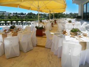 雅典德科里亚酒店的一组桌子,配有白色的椅子和遮阳伞