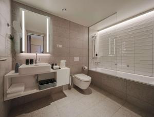 科隆Adina Apartment Hotel Cologne的浴室配有盥洗盆、卫生间和浴缸。