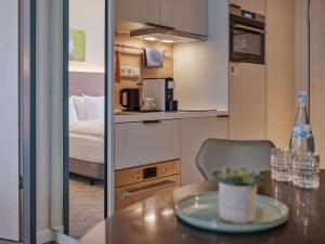 科隆Adina Apartment Hotel Cologne的小房间设有桌子和床