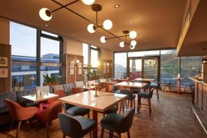 斯图加特Adina Apartment Hotel Stuttgart的餐厅设有桌椅和大窗户。