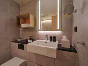 斯图加特Adina Apartment Hotel Stuttgart的浴室设有白色水槽和镜子